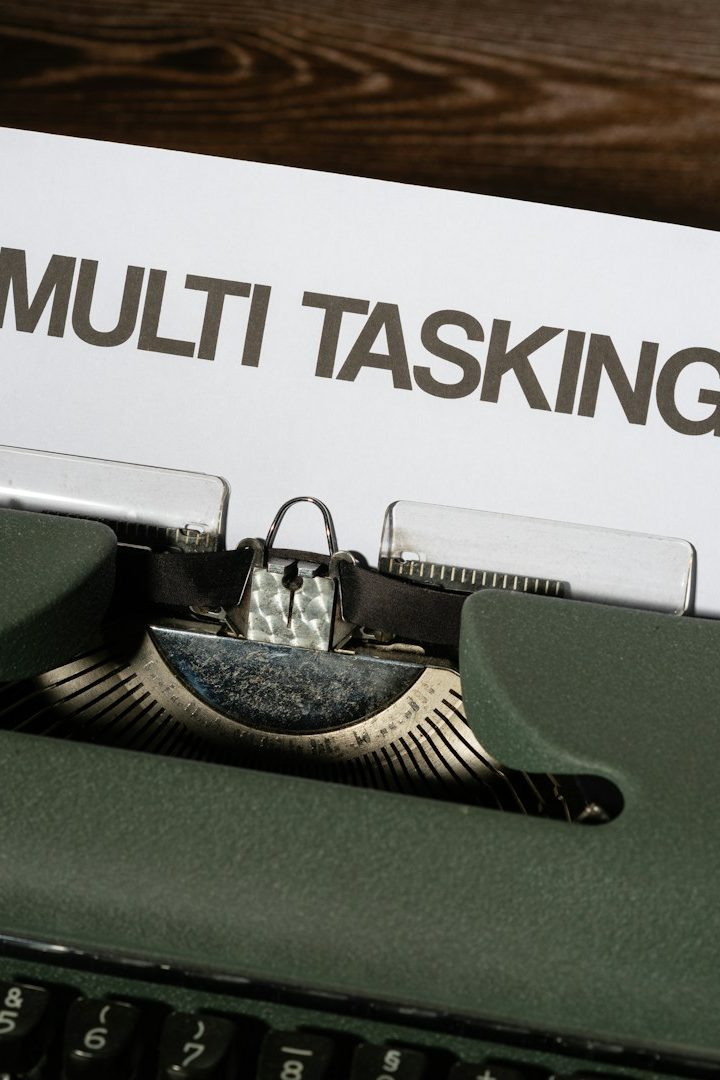Old-fashioned Schreibmaschine mit dem Schriftzug „MULTI TASKING“ im Hintergrund.