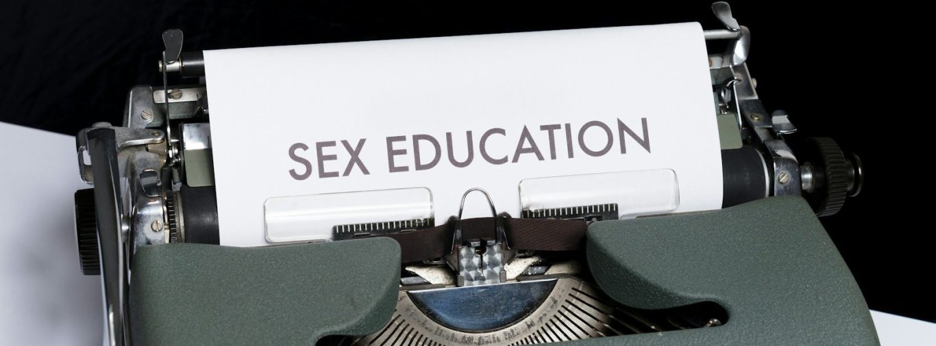 Schreibmaschine mit dem Blatt "SEX EDUCATION" im Vordergrund.