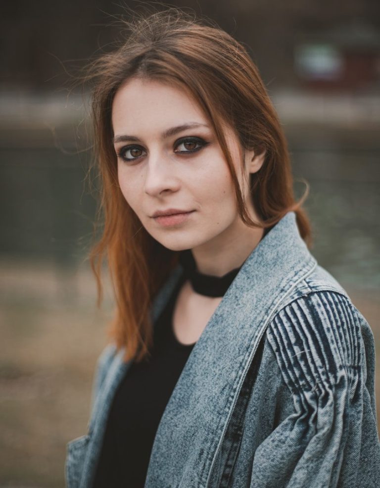 Porträt einer Frau mit langen, braunen Haaren, die einen grauen Mantel trägt.
